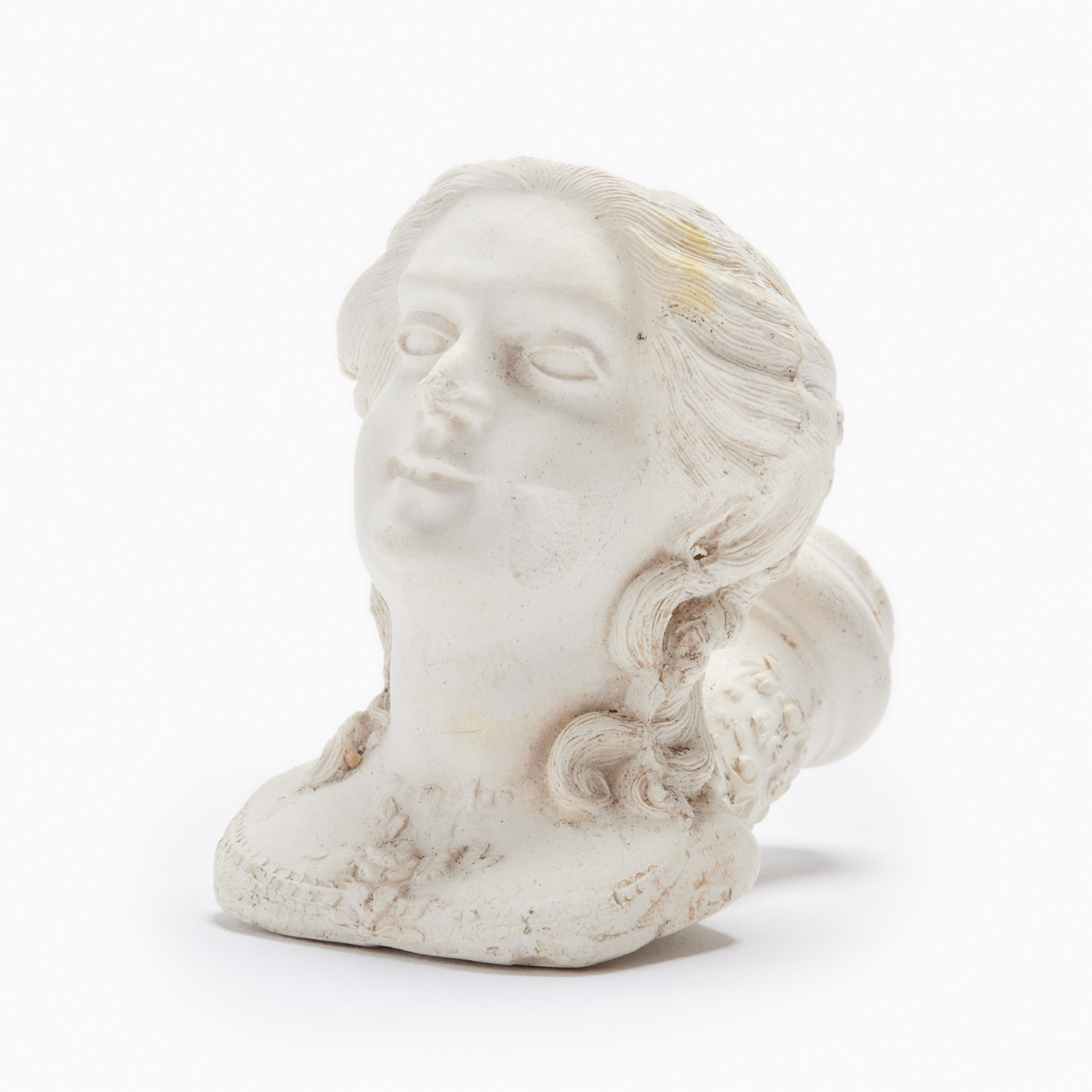 A miniature white bust sculpted of clay, this woman is merely a head with a tumble of finely-carved hair pulled back into the shape of a smoking pipe with a hole at the top. 