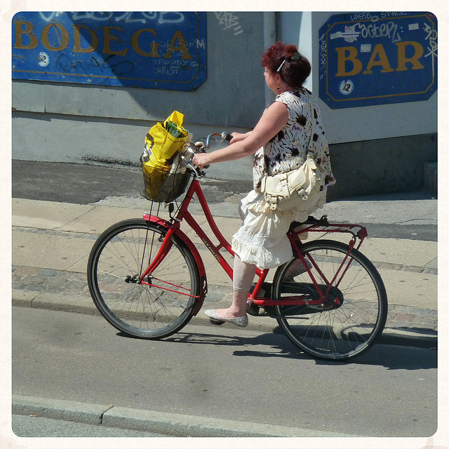 A lady on a step through bicycle rides her groceries home.