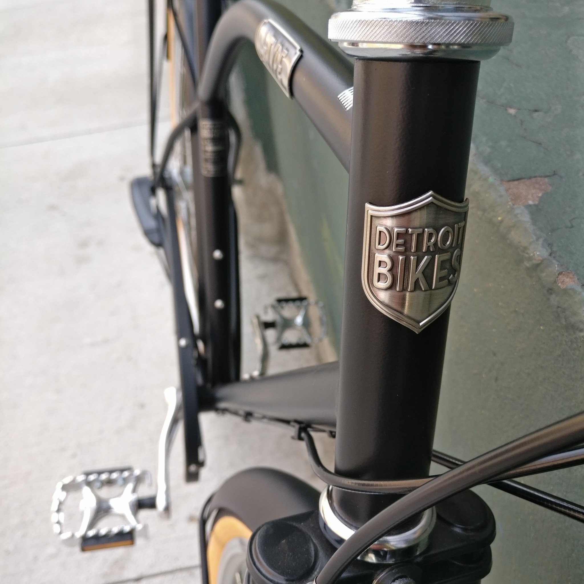 A closeup of the Detroit Bicycles head badge on a black bicycle.