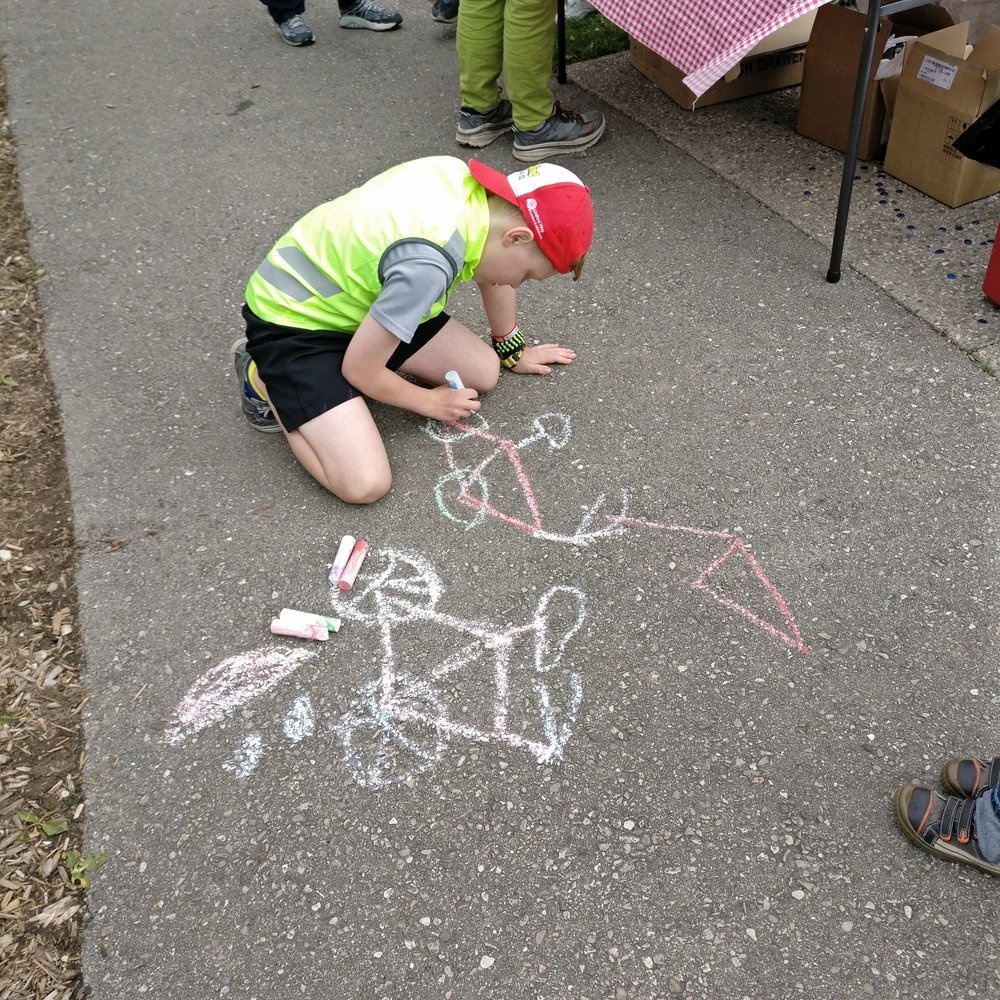 A boy chalks images of bicycles onto asphalt