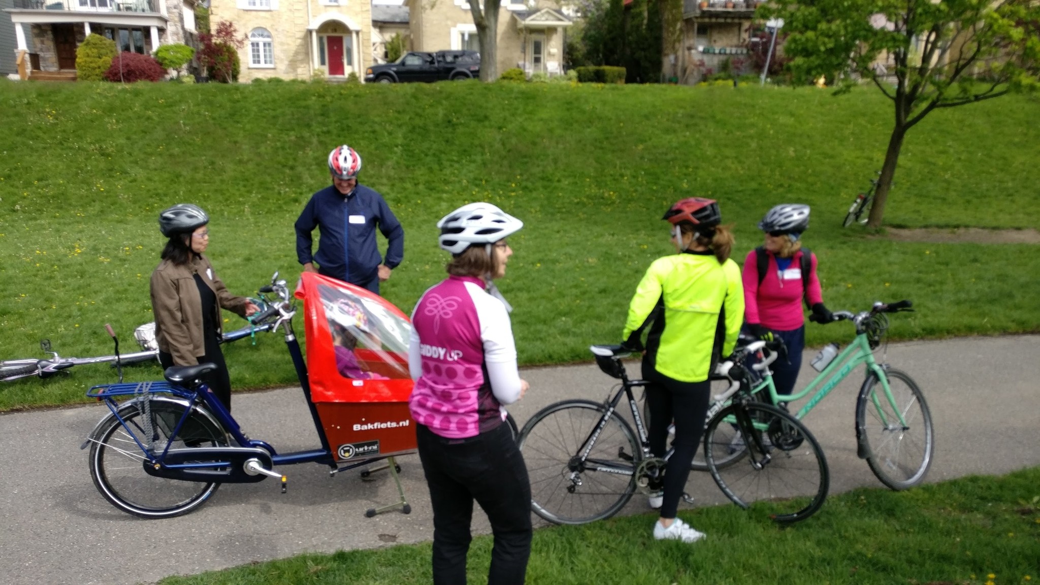 A group of cyclists stops to chat, they have a bakfiets box bike among other more typical bikes.