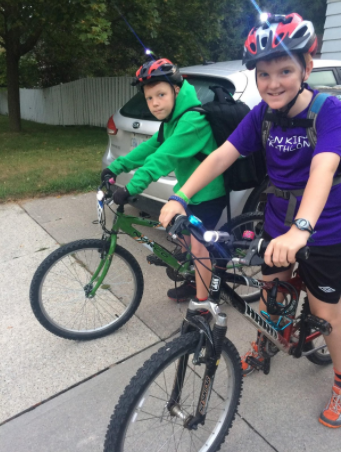 The same two kids smiling from their bike seats just before they get going on their ride to school.