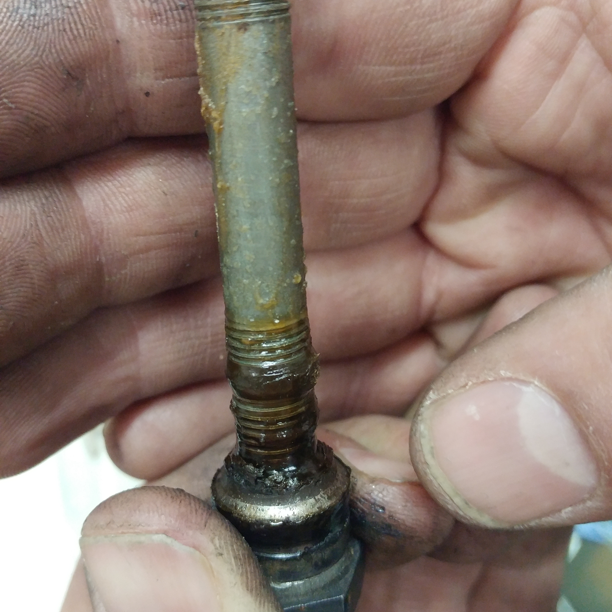 Two hands hold up a bicycle axel that is in poor repair.