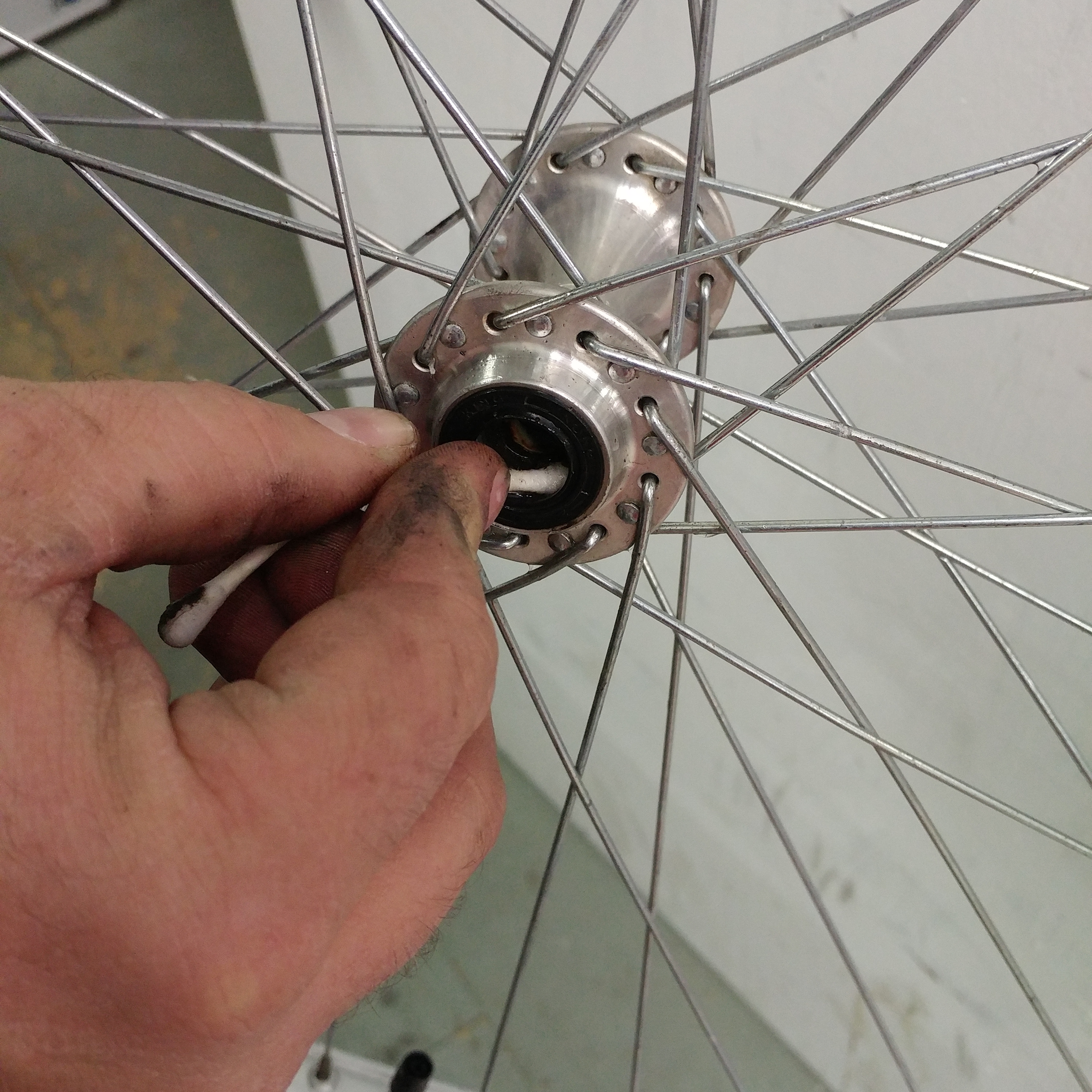 A q-tip is being used to clean out the axel of a bicycle wheel.