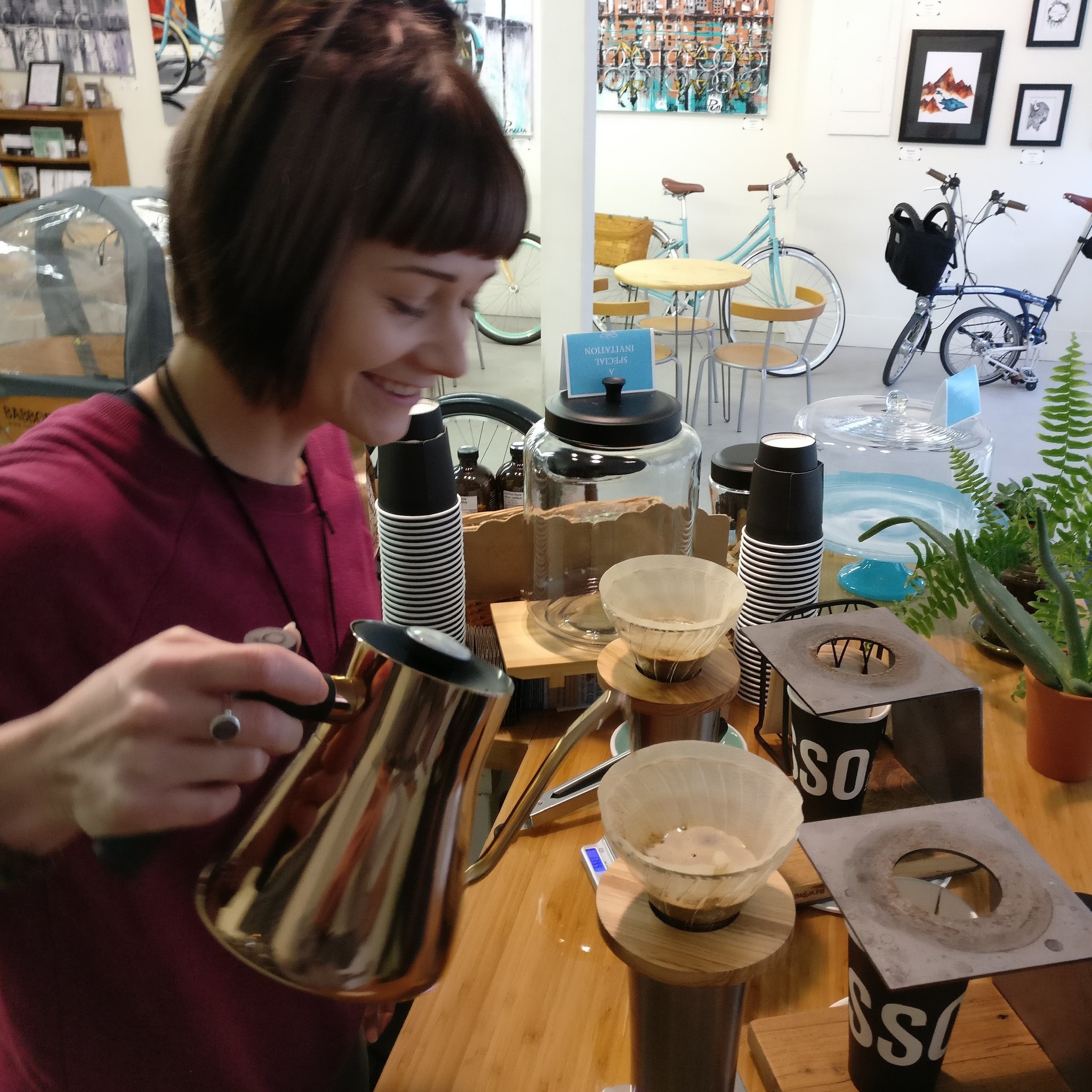 Jen smiles as she makes a pourover coffee at the coffee bar.