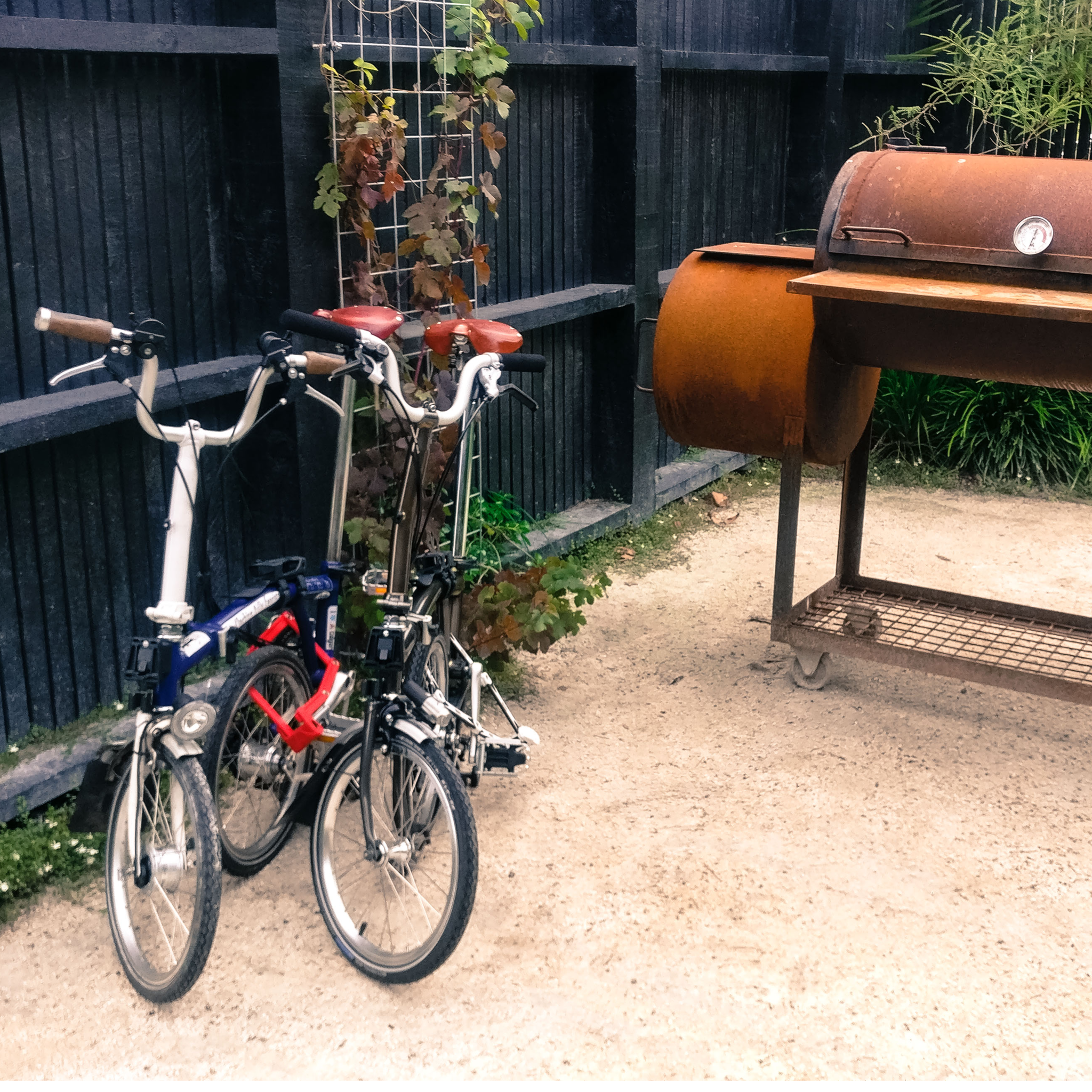 Two Bromptons next to a classic barbeque.