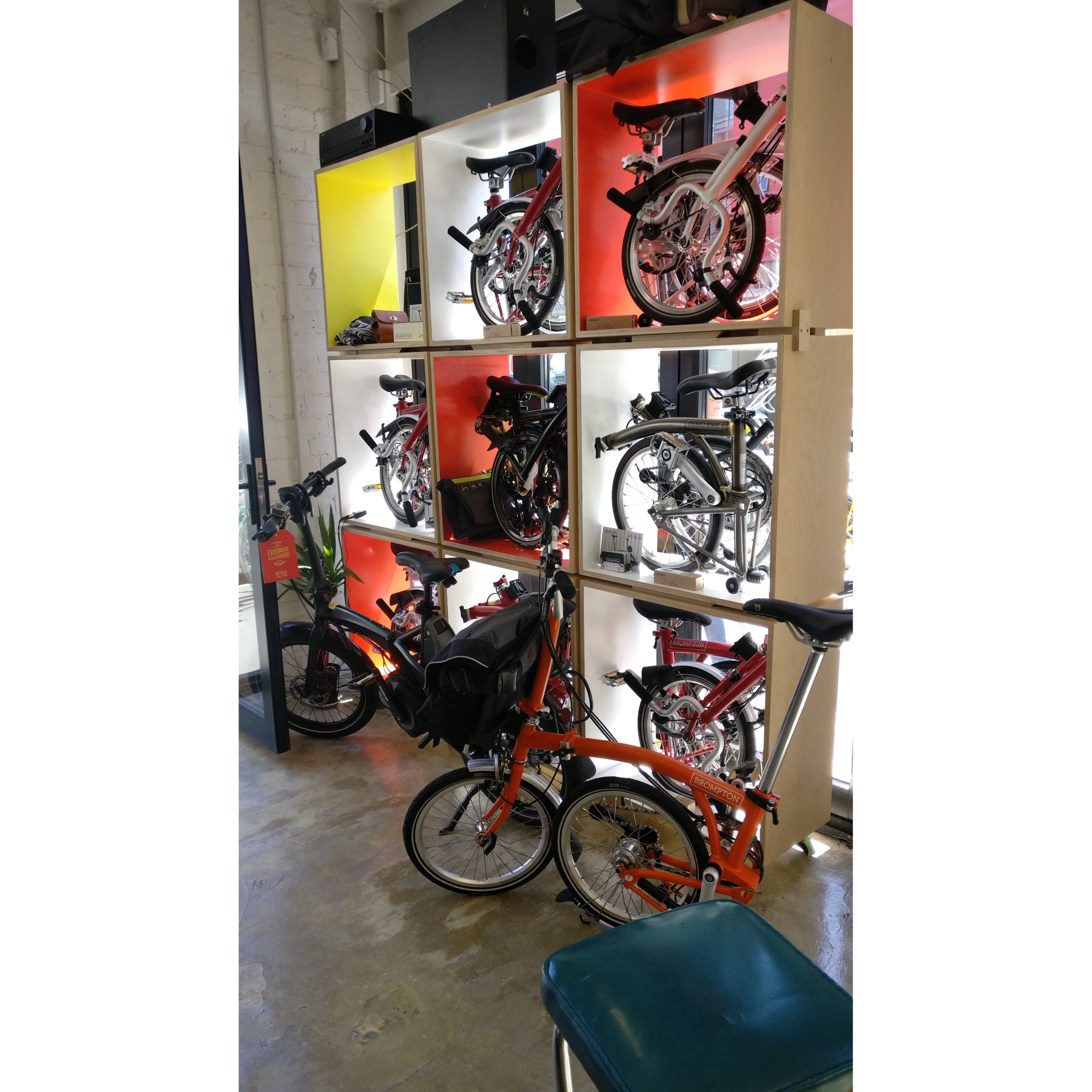 The Brompton cubes holding their folded bikes, but from inside the shop.