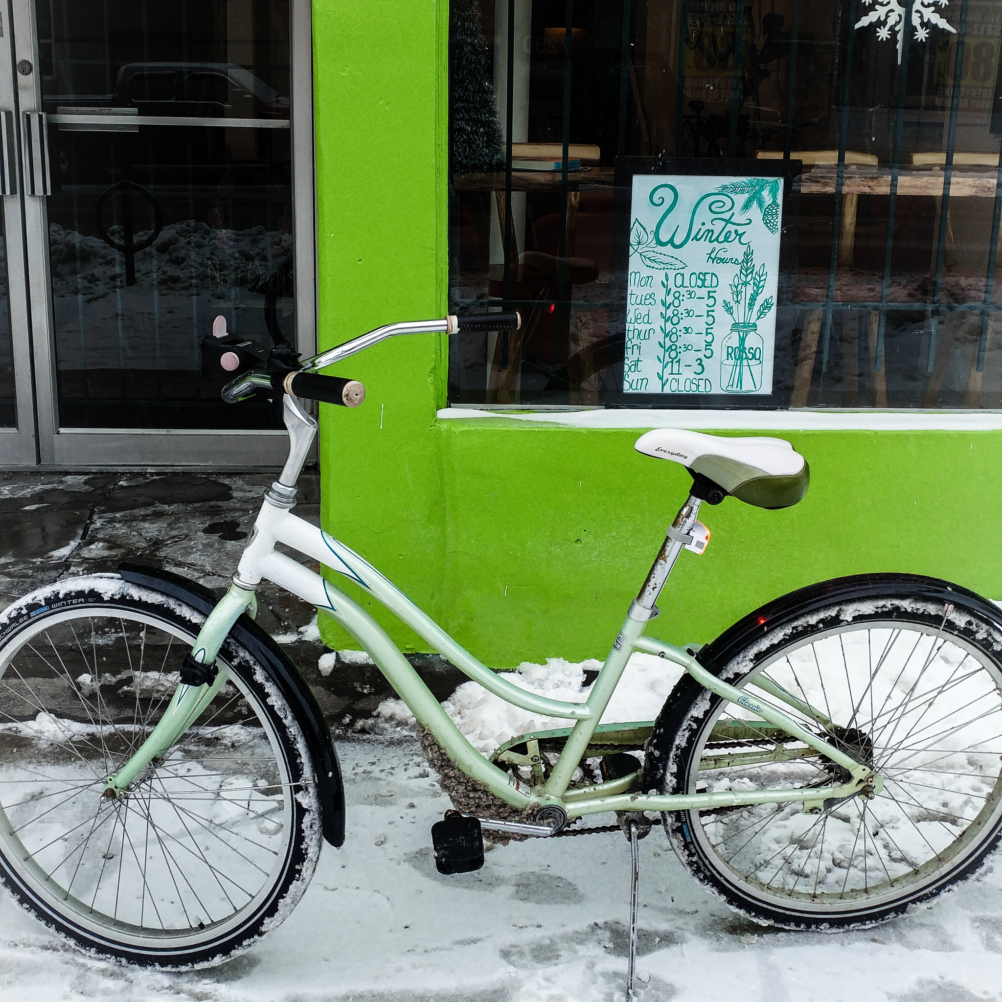 A cruiser bike in front of the shop with a "winter hours" sign in the window.