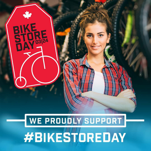 A woman smiles with her hands folded across her chest, the text "We support bike shop day" in front of her.