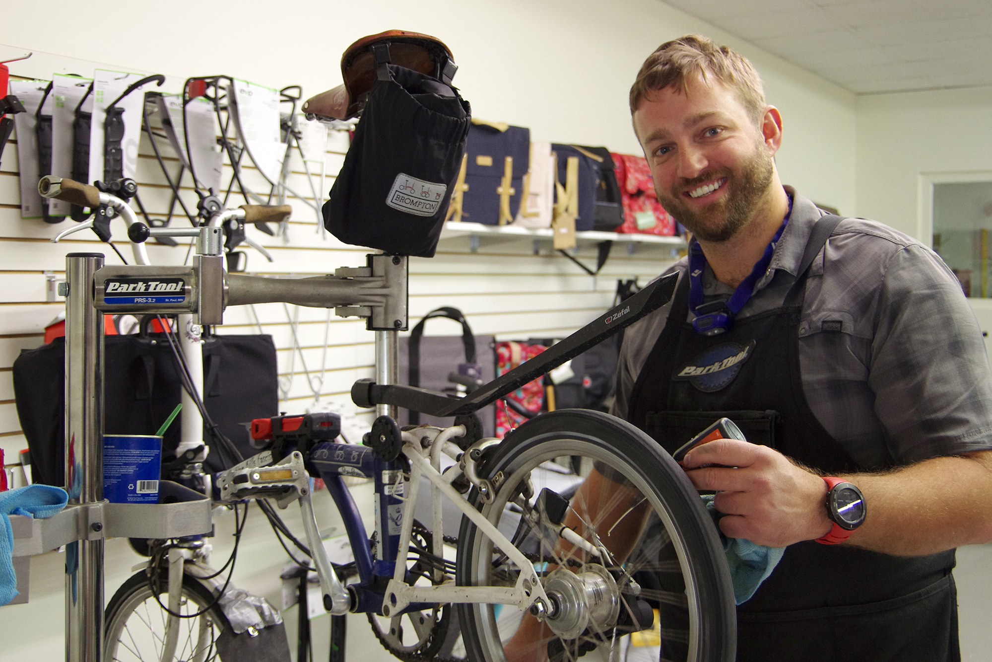 Ben smiling at the bike stand as he applies Tri-Flow to the bike chain there.