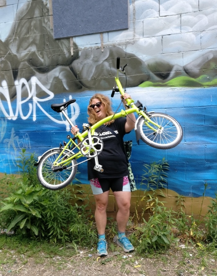 Shelley holds her lime green Brompton in front of her victoriously