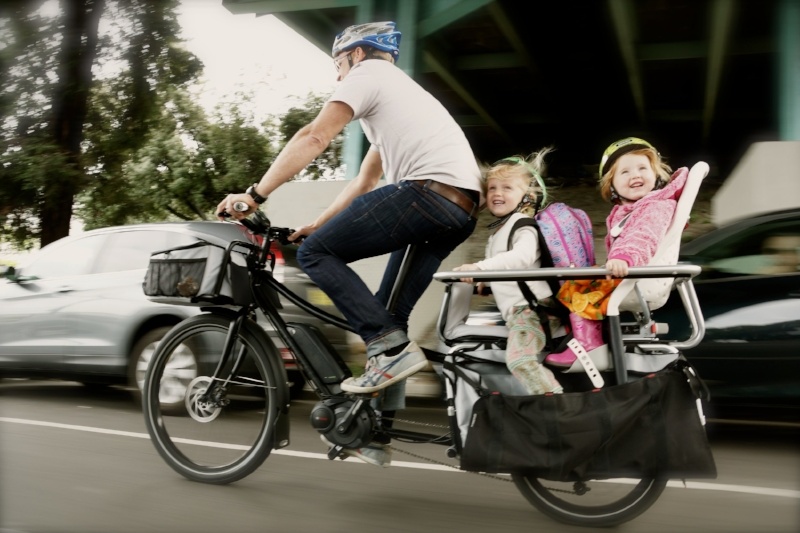 Two small children enjoy a fast ride on the back of an Xtracycle e-bike.