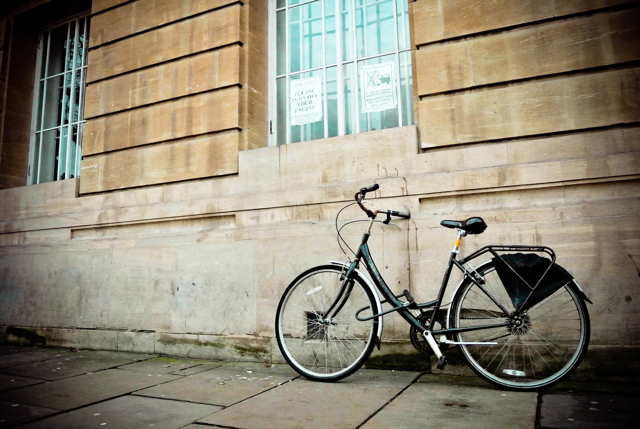 A cruiser bike leans against a beige cement wall.