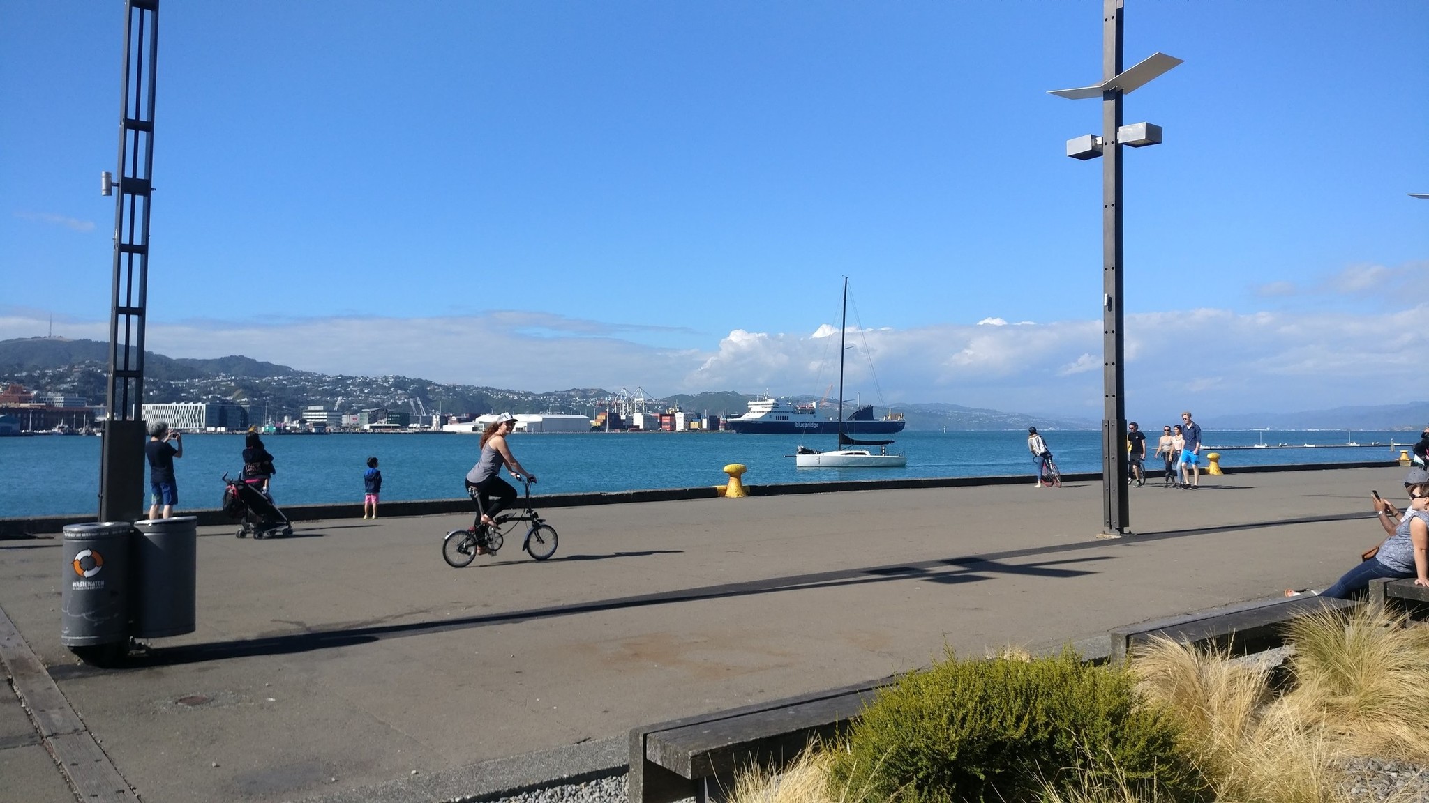 A lady on a Brompton rides a seawall path.