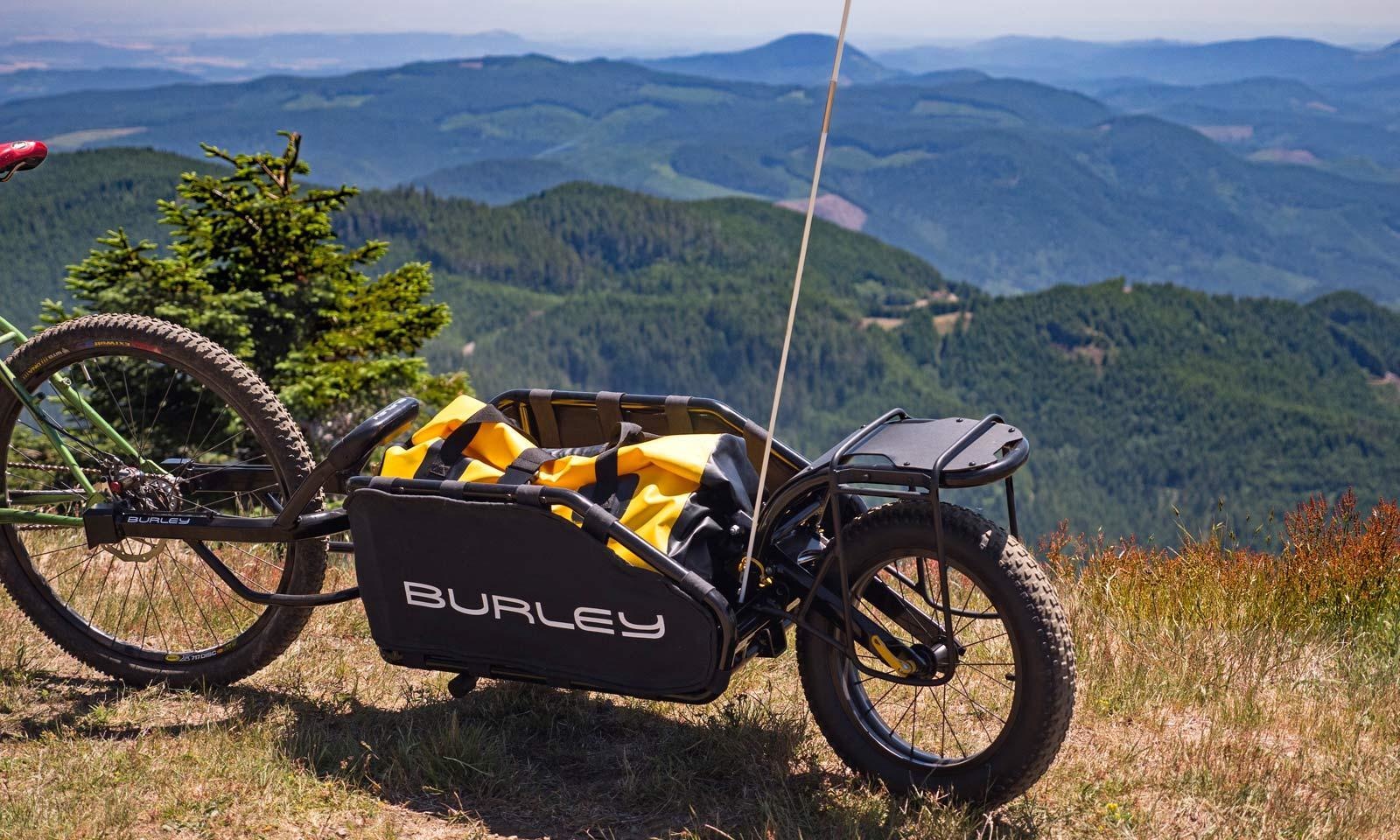 A Burley Cargo trailer near the edge of a cliff, a beautiful natural vista beyond.