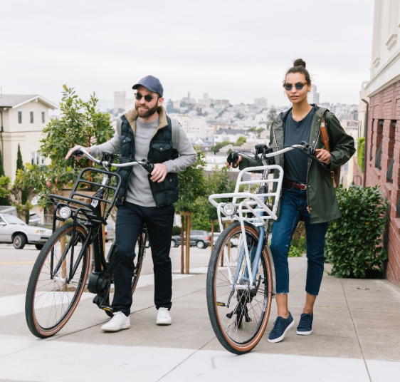 A man and woman stand next to their bikes facing the camera and smiling