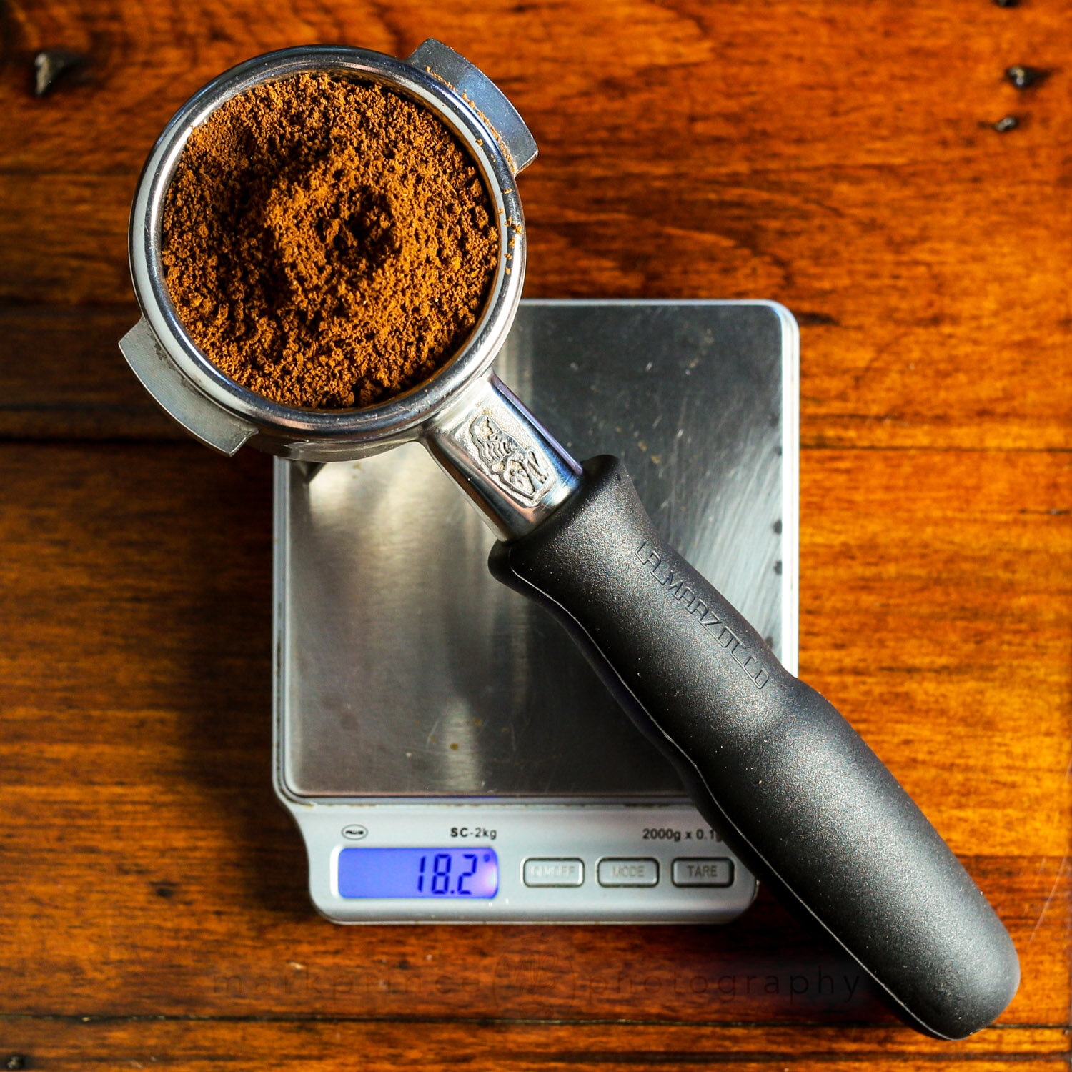 A full espresso portafilter sits on an AWS scale.