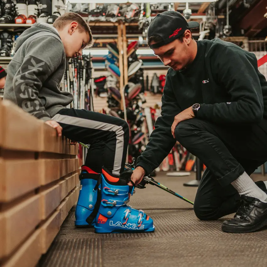 un enfant fait une location de ski à la saison en boutique, il essaie des bottes