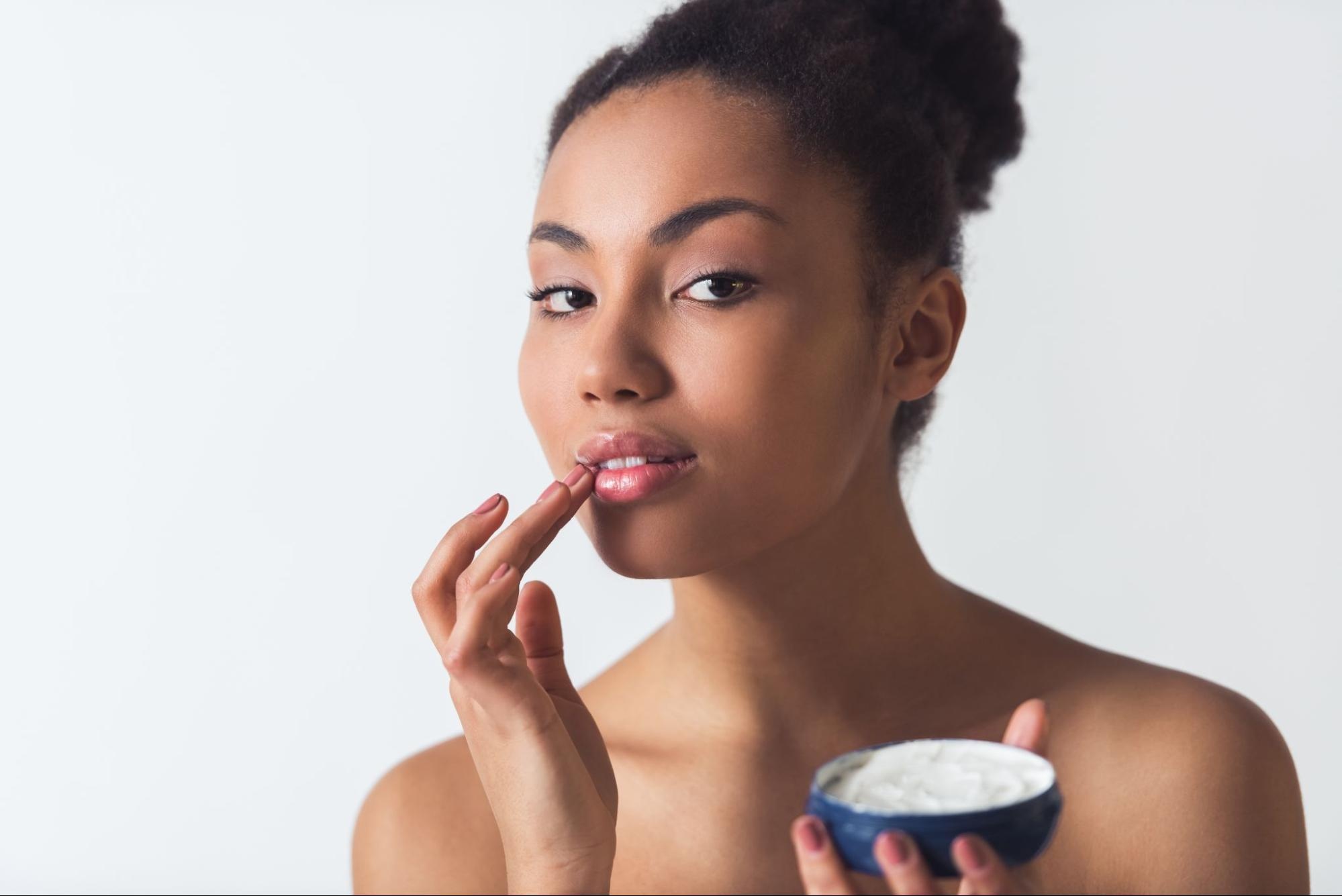 Woman uses lip products on her bottom lip.