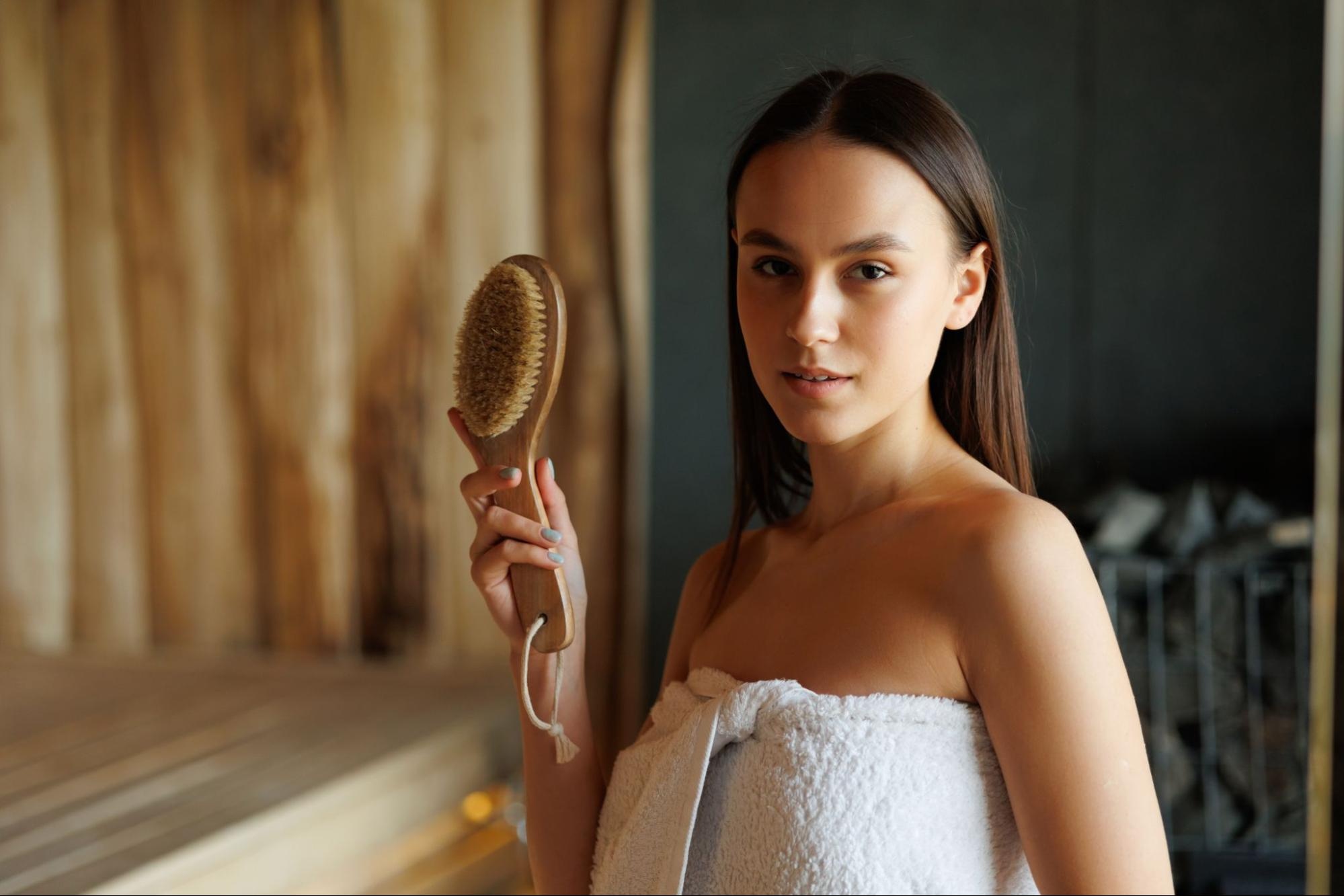  A woman holding a dry body brush in a sauna
