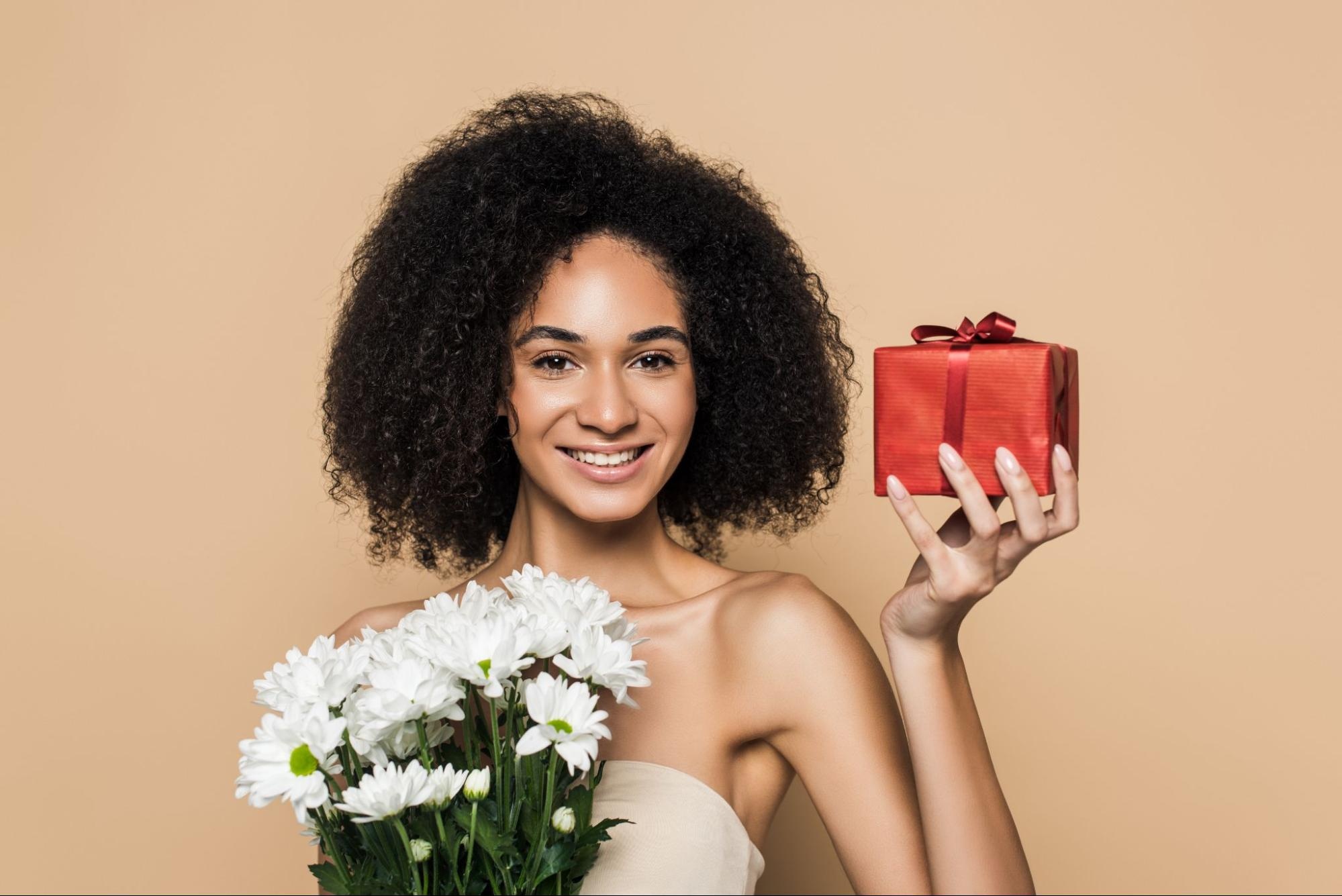 Woman holding flowers and a wrapped gift. 