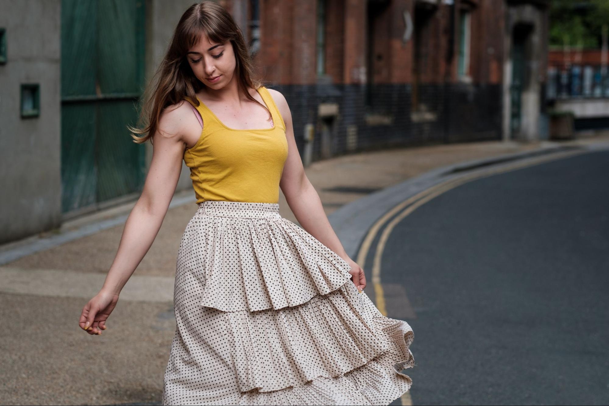 A young woman in a tiered skirt posing in the street.