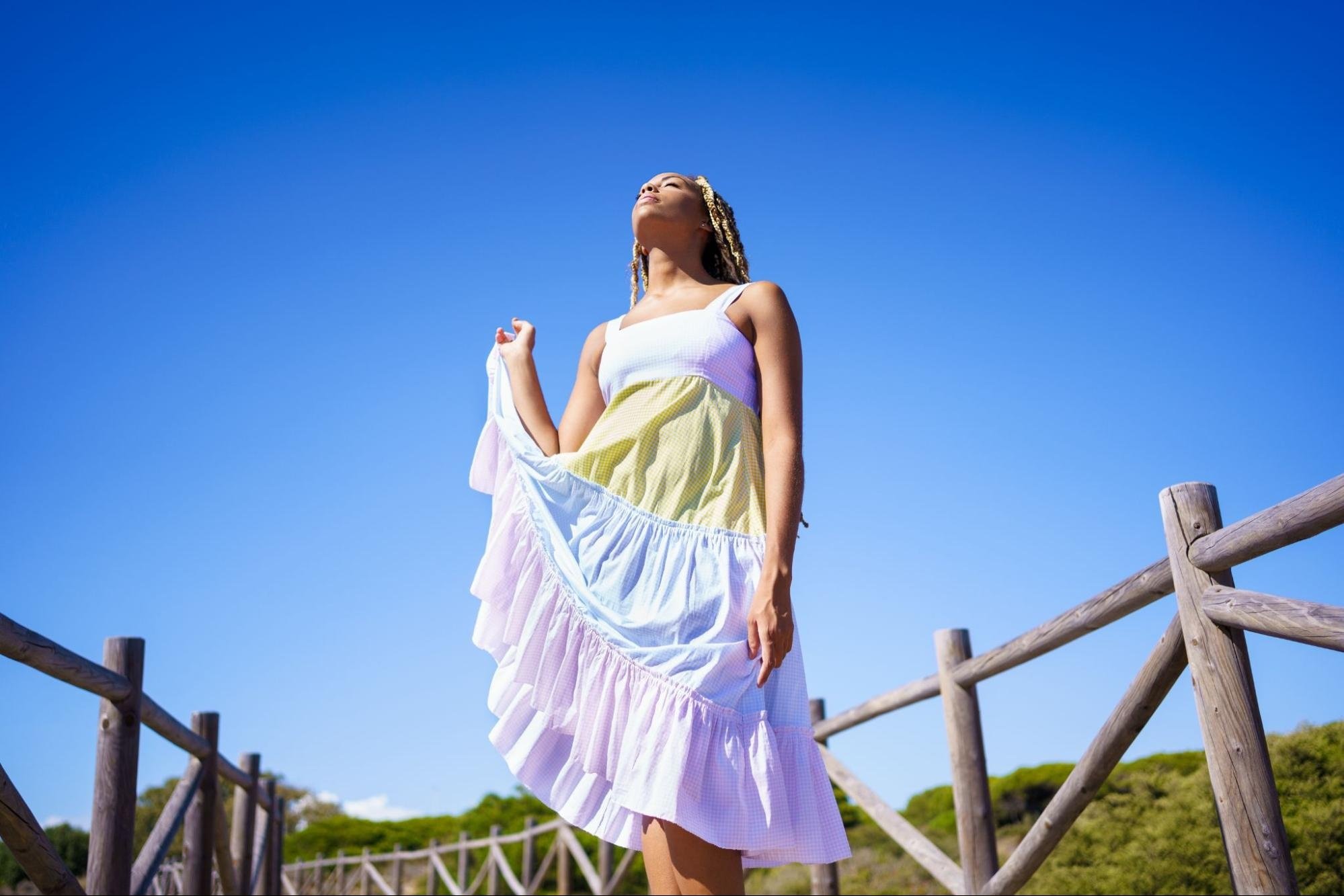 A woman wearing a tiered skirt posing on a beach boardwalk.