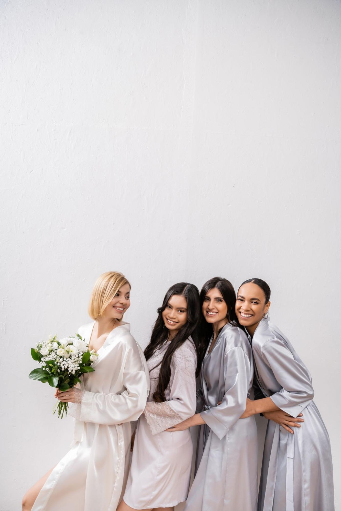 Bride and bridesmaids in robes standing side-by-side. 
