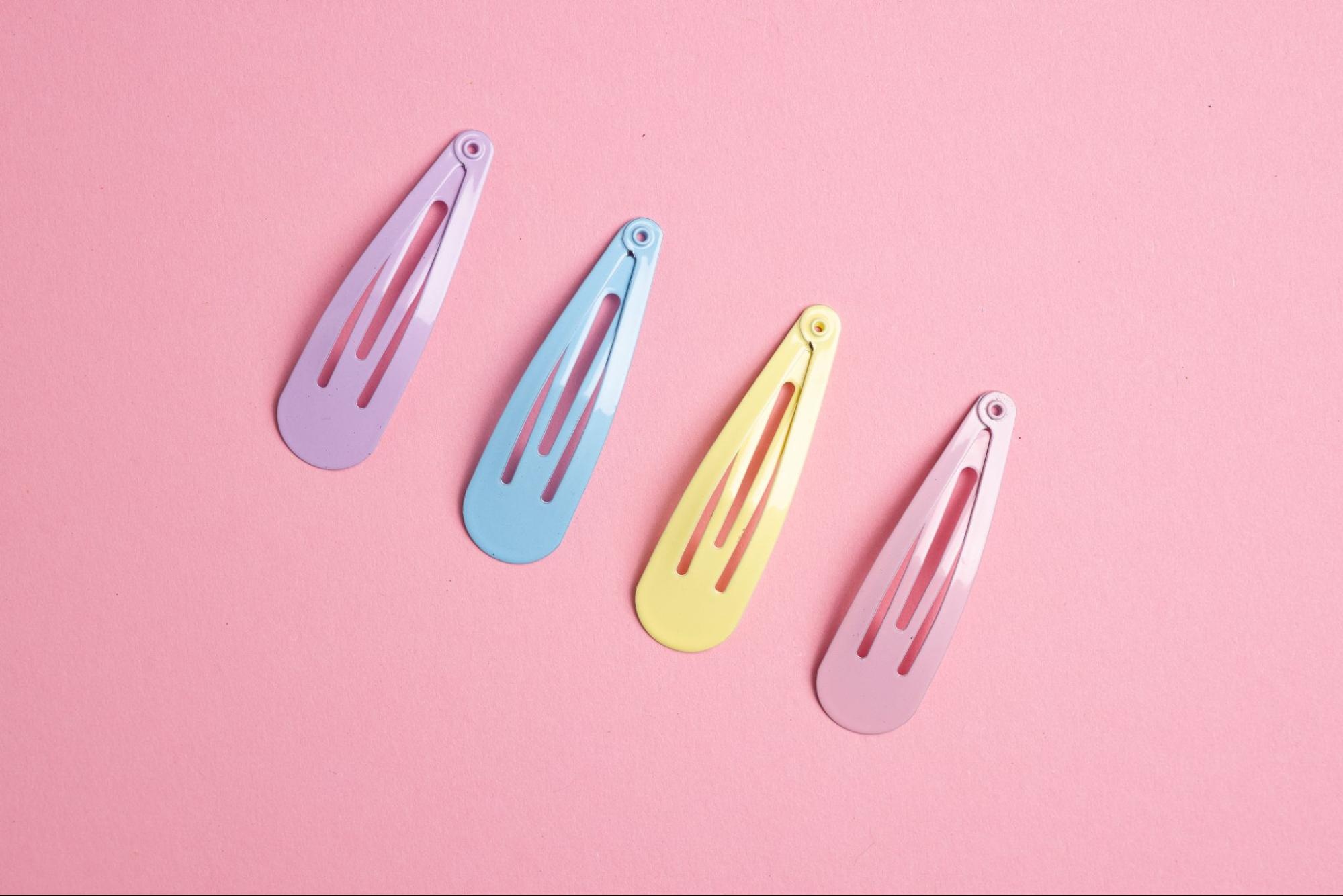 An assortment of hair pins against a pink background.