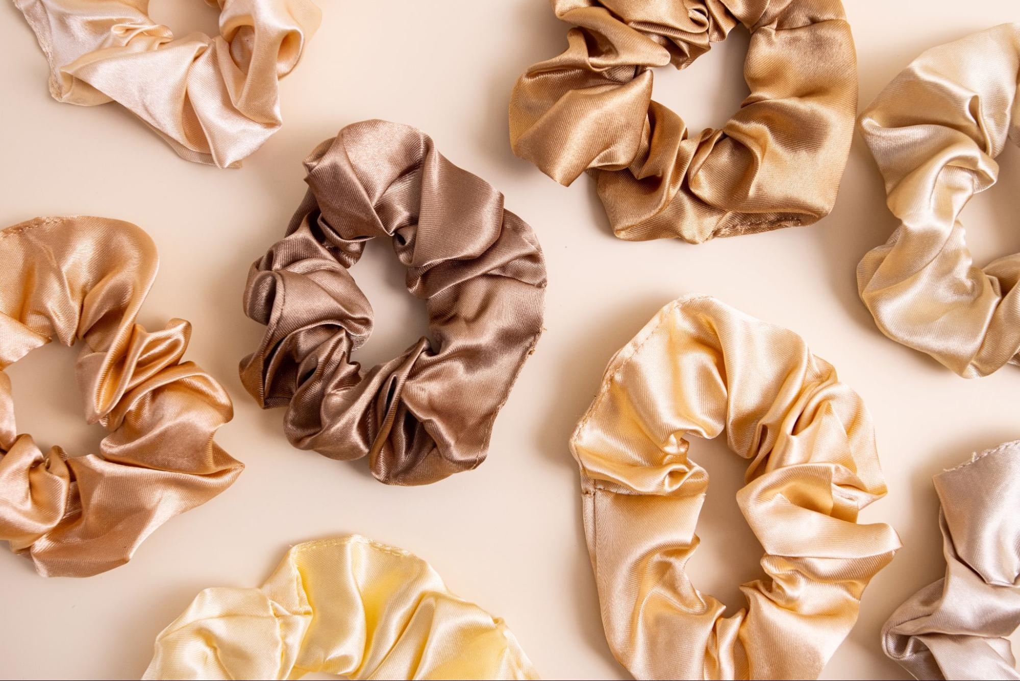 An assortment of hair scrunchies against a beige background.