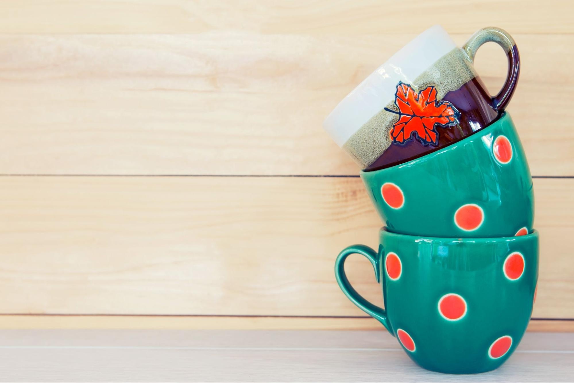 Fall mugs stacked on top of each other with wood in the background. 