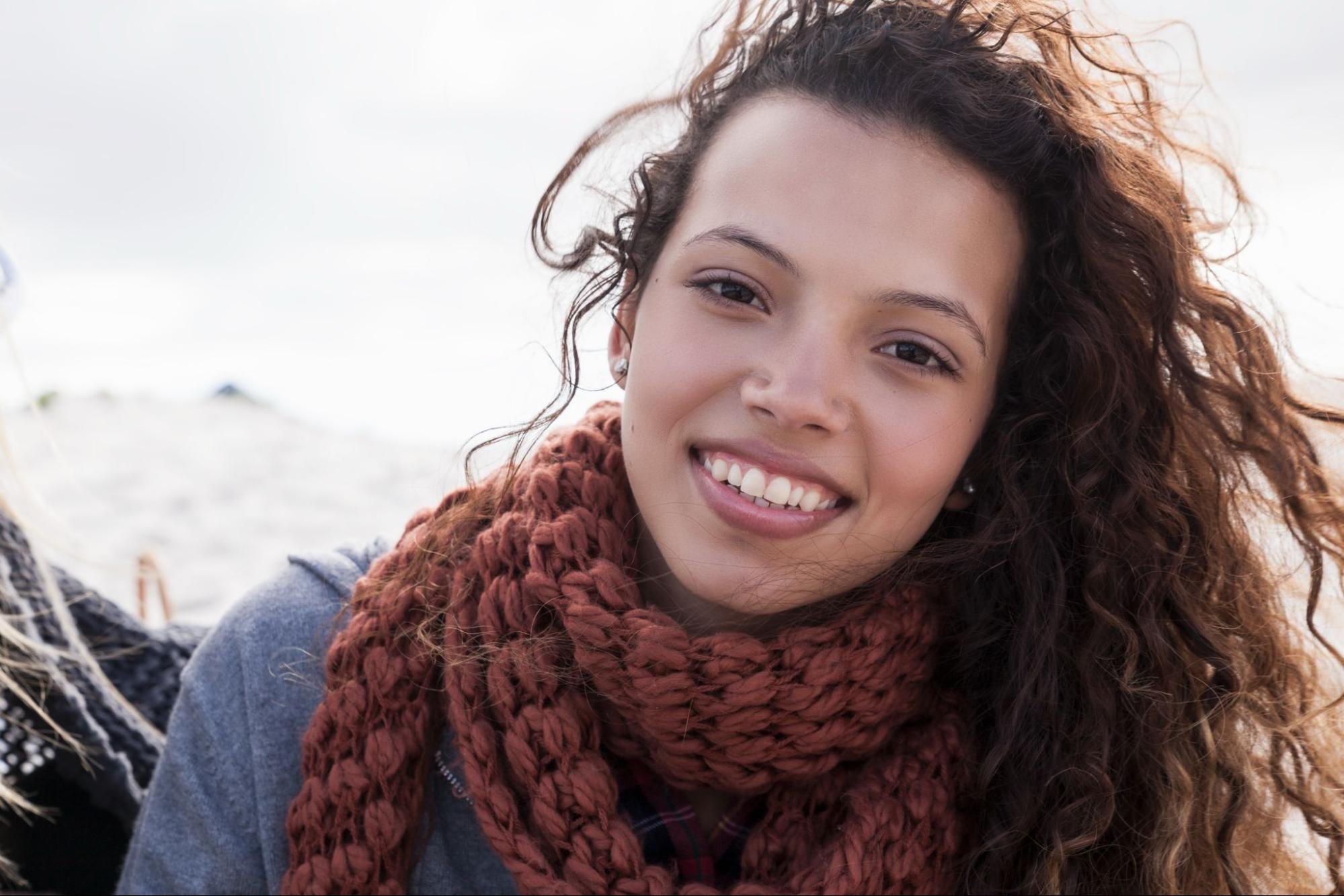 Woman smiling and wearing a knitted scarf. 