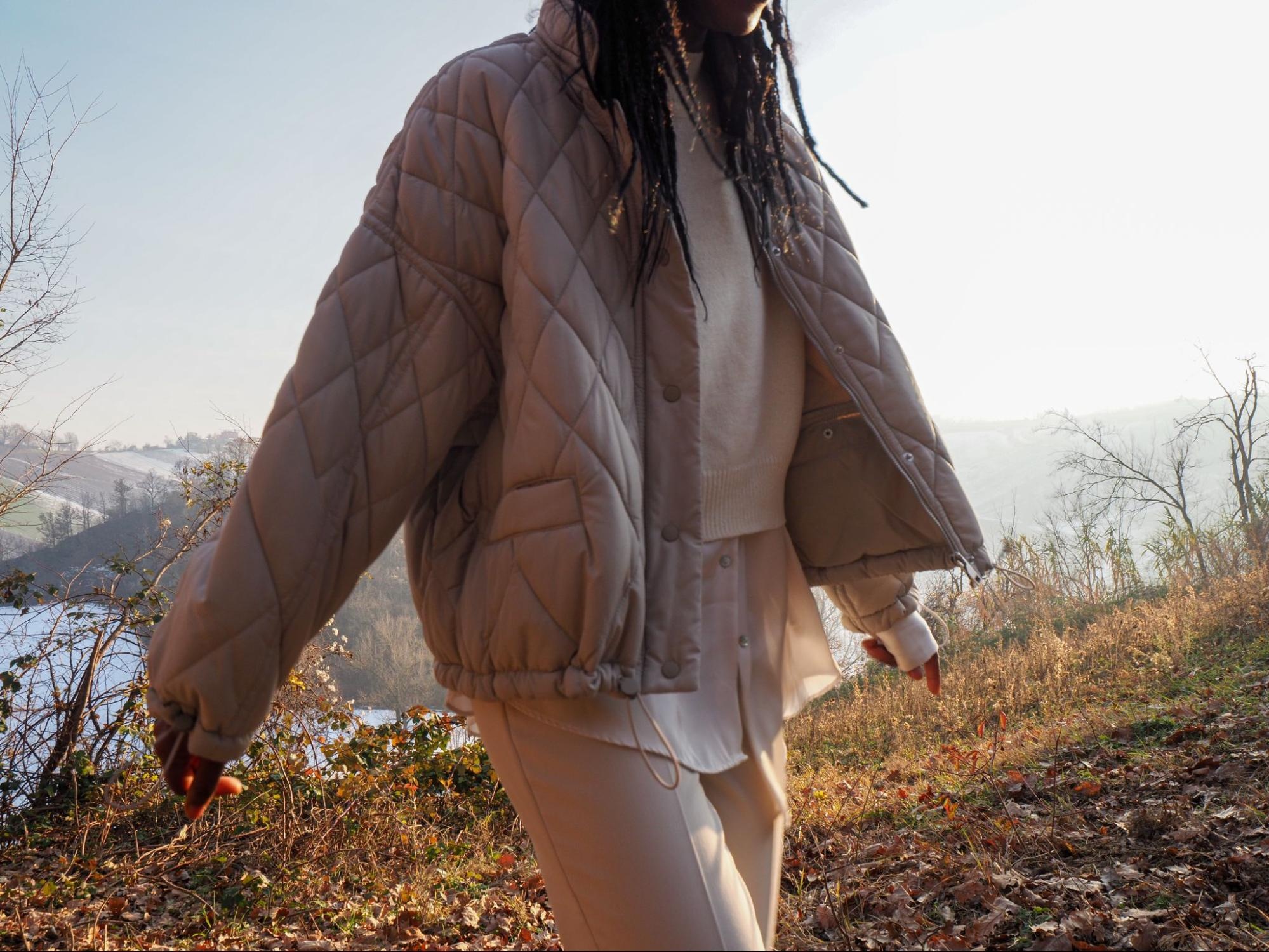 A cropped shot of the upper body of a woman wearing a quilted jacket.