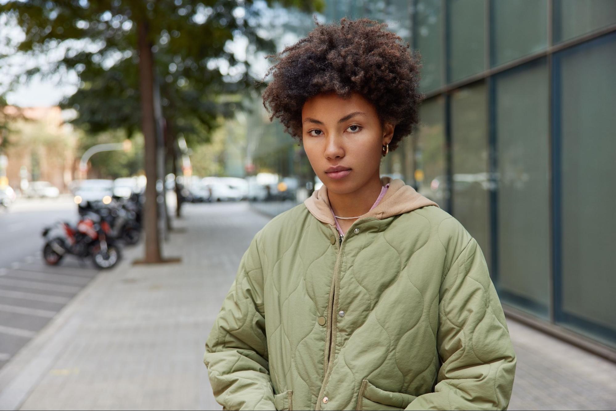 A crop-shot of a curly-haired woman wearing a quilted jacket.