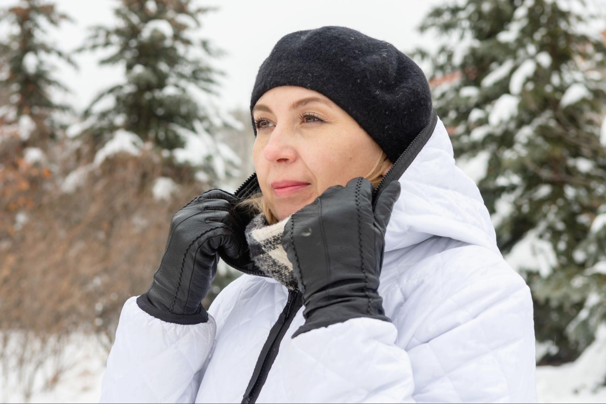 Woman in winter gloves and a puffy jacket in the snow. 