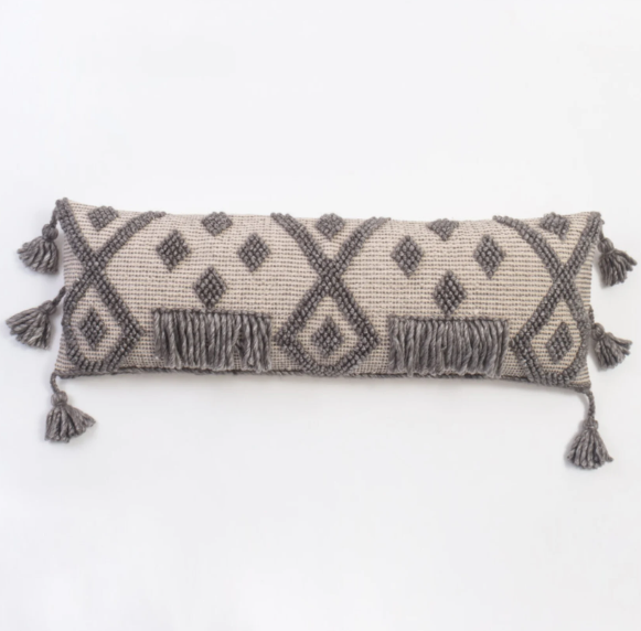 Carlos Bolster Pillow on bed with neutral linens and layered textures