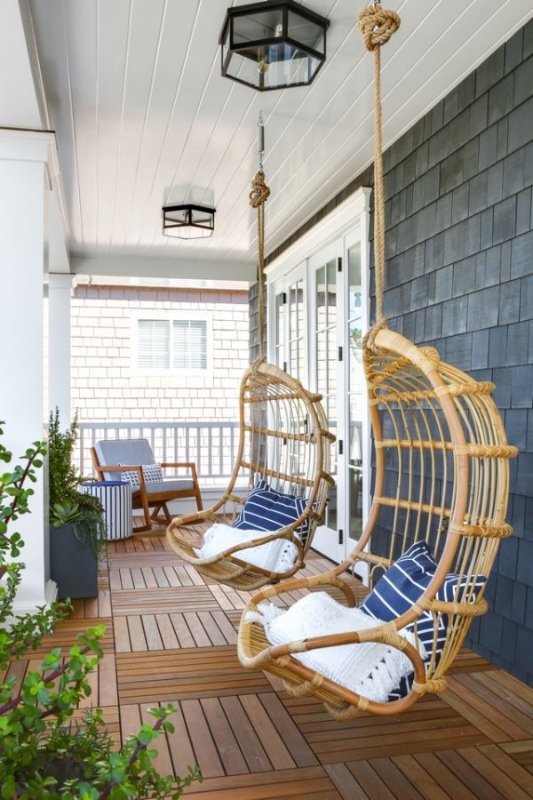 Gray home with rattan hanging porch chairs.