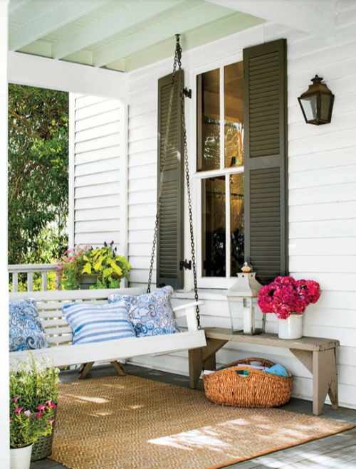Home with olive shutters and colorful porch furniture. 
