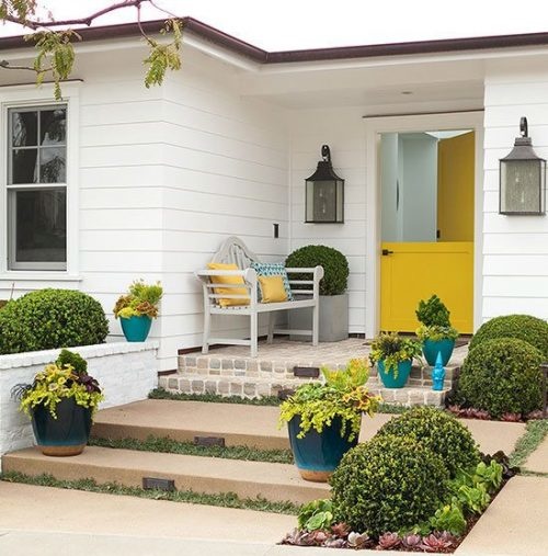 Home with yellow door and porch furniture. 