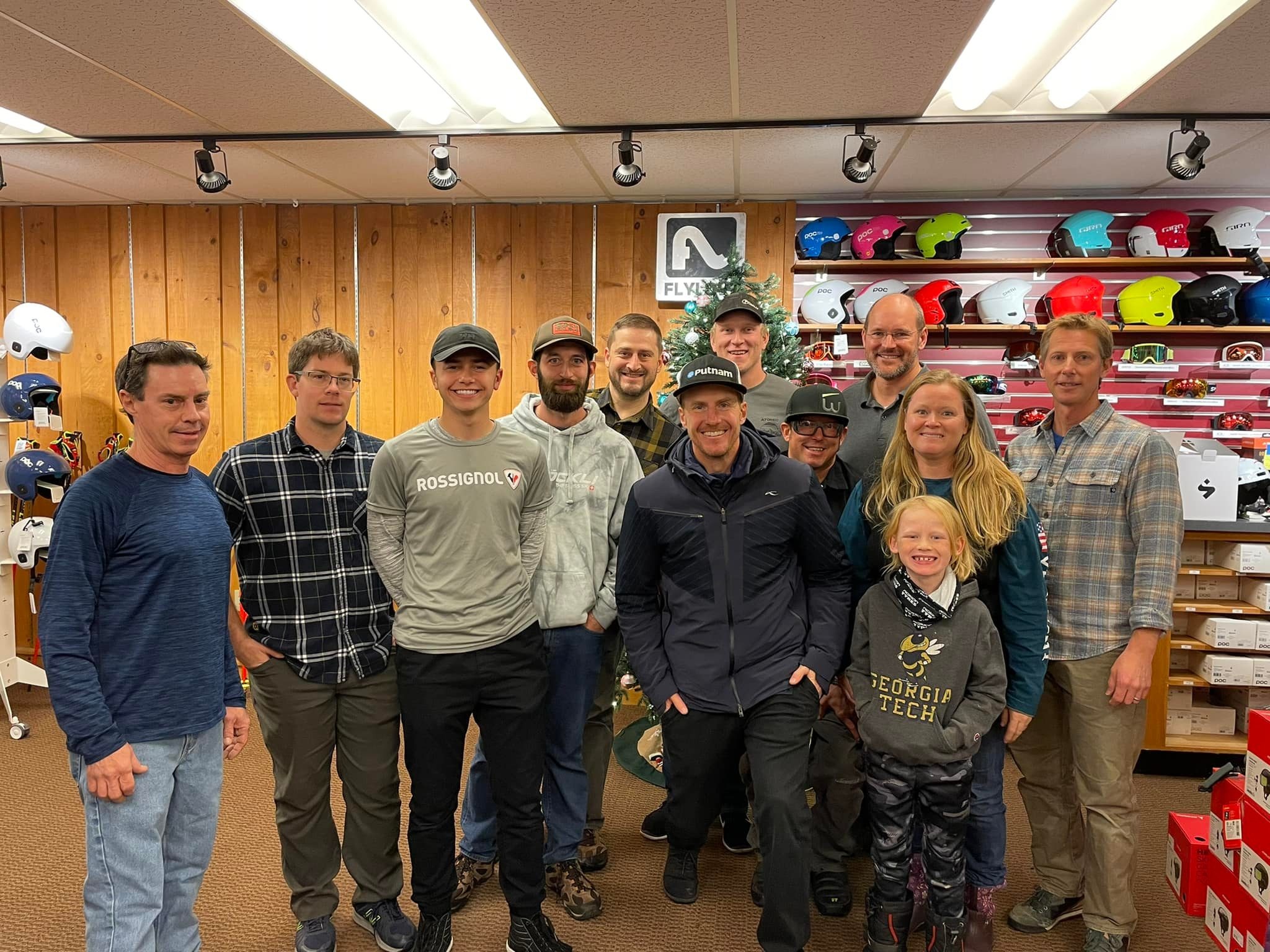 Peak Performance Ski Shop team stands in the ski rental and tuning shop among helmets, skis, poles, goggles, and other ski equipment