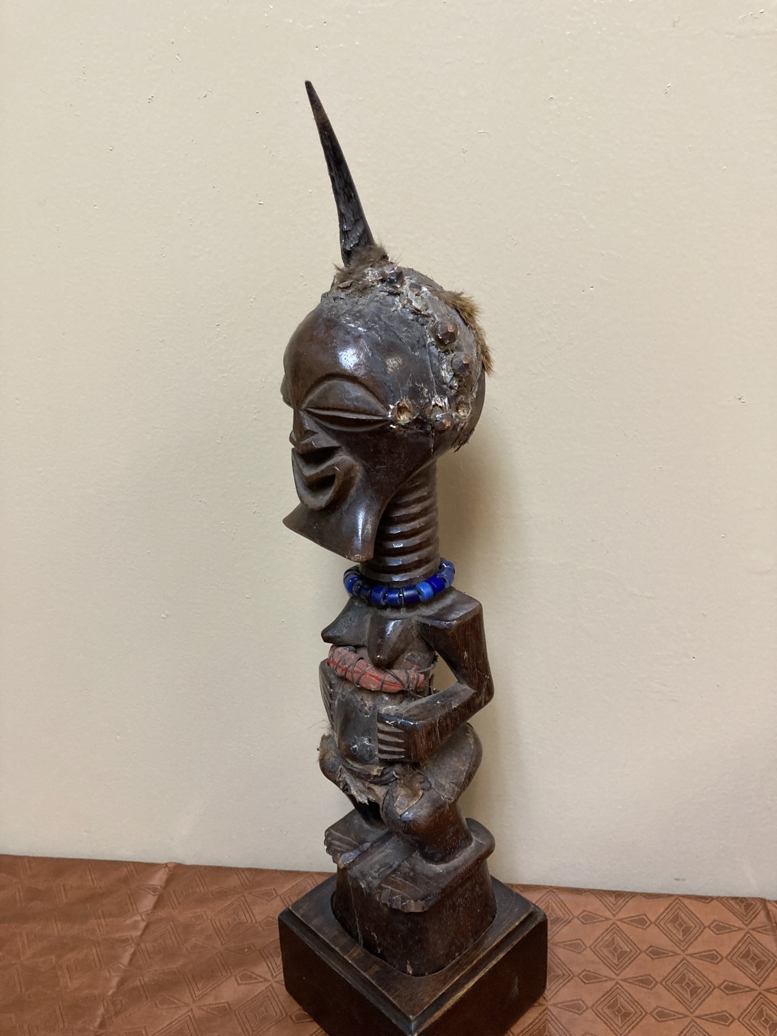 Songye or Basonge wooden figure: This fine figure had the job of protection. It's wooden with horn , blue beads or cotton fabric. The sculpture is 17 5/8" h including the base. The Songye are found in