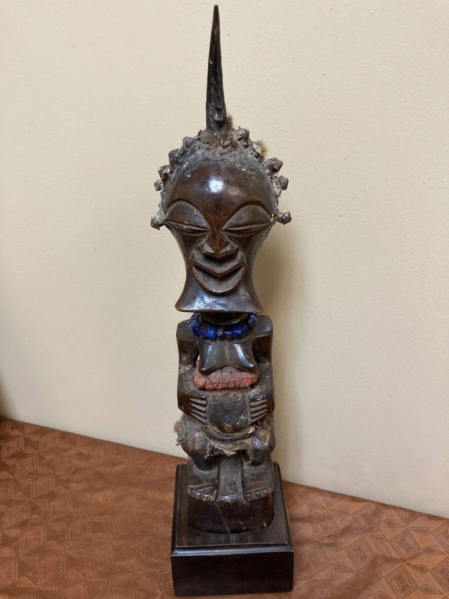 Songye or Basonge wooden figure: This fine figure had the job of protection. It's wooden with horn , blue beads or cotton fabric. The sculpture is 17 5/8" h including the base. The Songye are found in