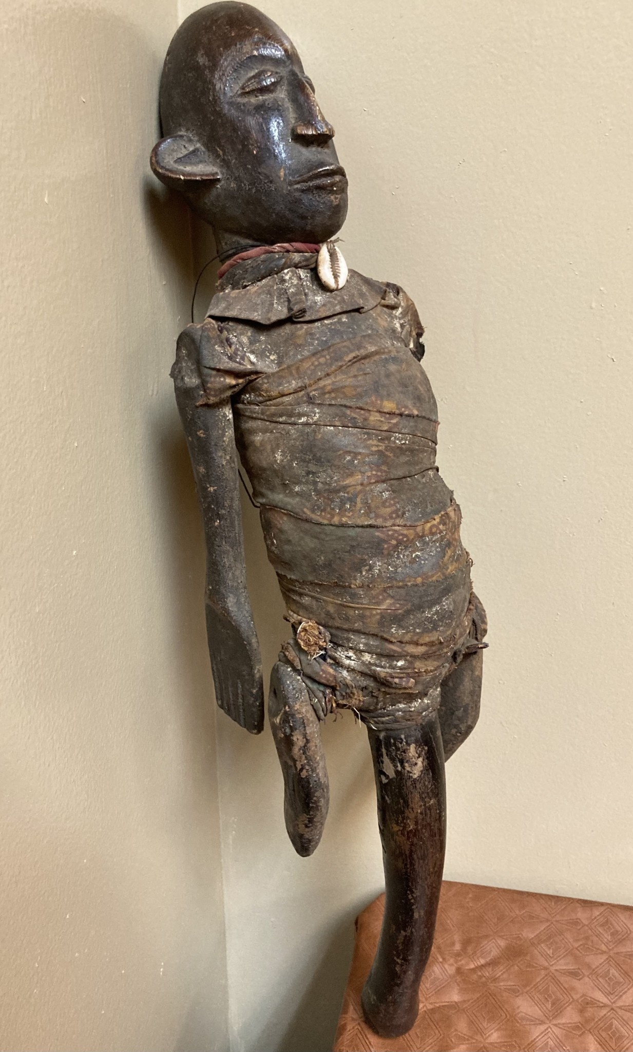 Makonde figure with handle. The Makonde live in East Africa in Mozambique, Tanzania with a small group in Kenya. This figure is used by entertainers and storytellers. Wood with cotton fabric and a cow