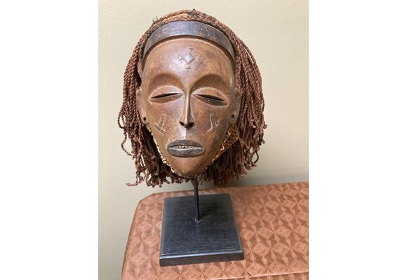 “Mwana Pwo” mask of the Chokwe (Tchokwe or Bajokwer) of Angola. Pwo is their word for woman. It represents a young woman who has been fully trained and is ready for marriage. Stand is included. Total