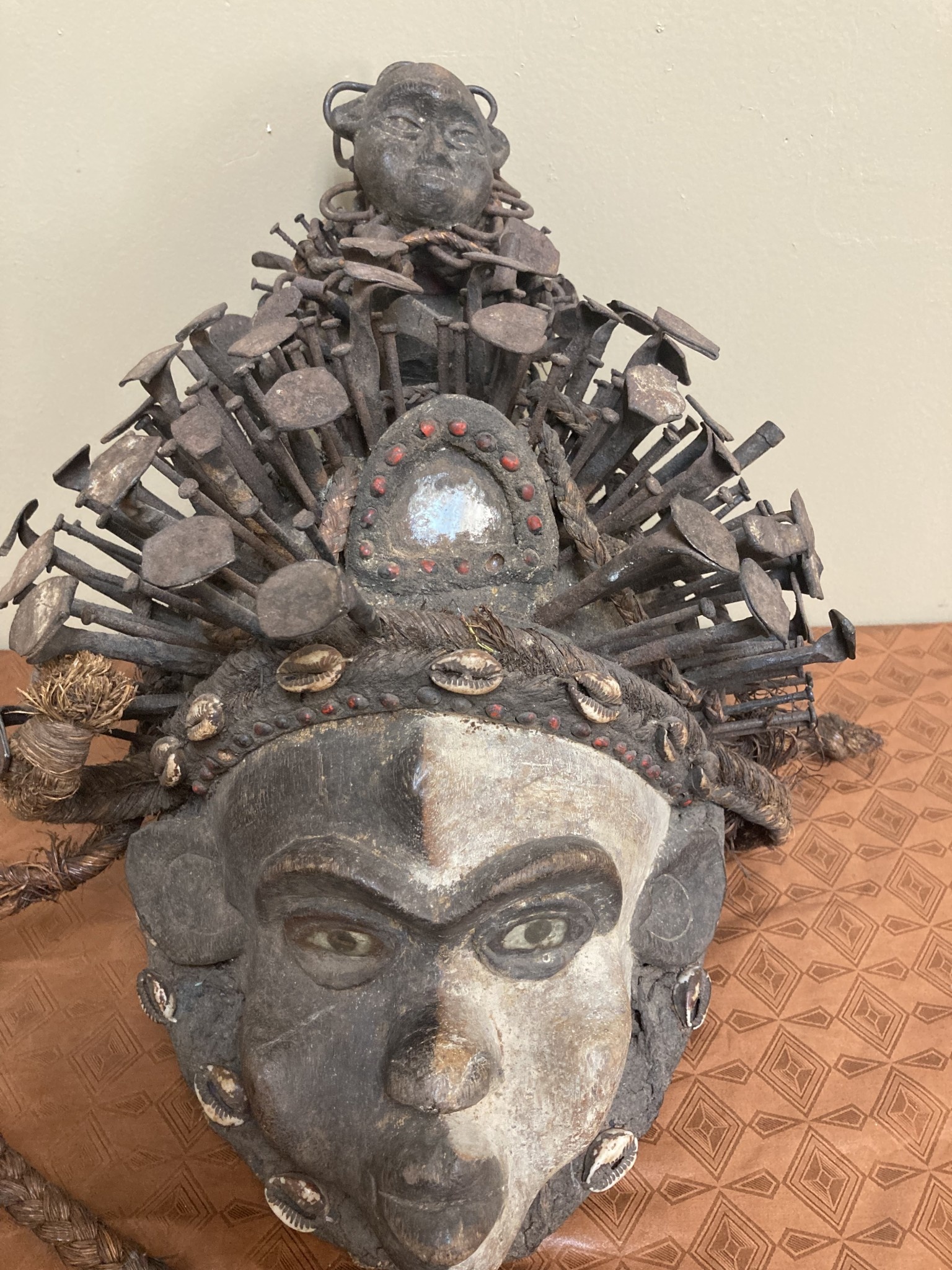 Kongo (Bakongo) wooden power figure or “Nkisi” Mask. It is decorated with cowrie shells, twine, iron nails, glass, and seeds. The Kongo ethnic group is found in Dem Rep of Congo. 16 ½ “ x 11 “