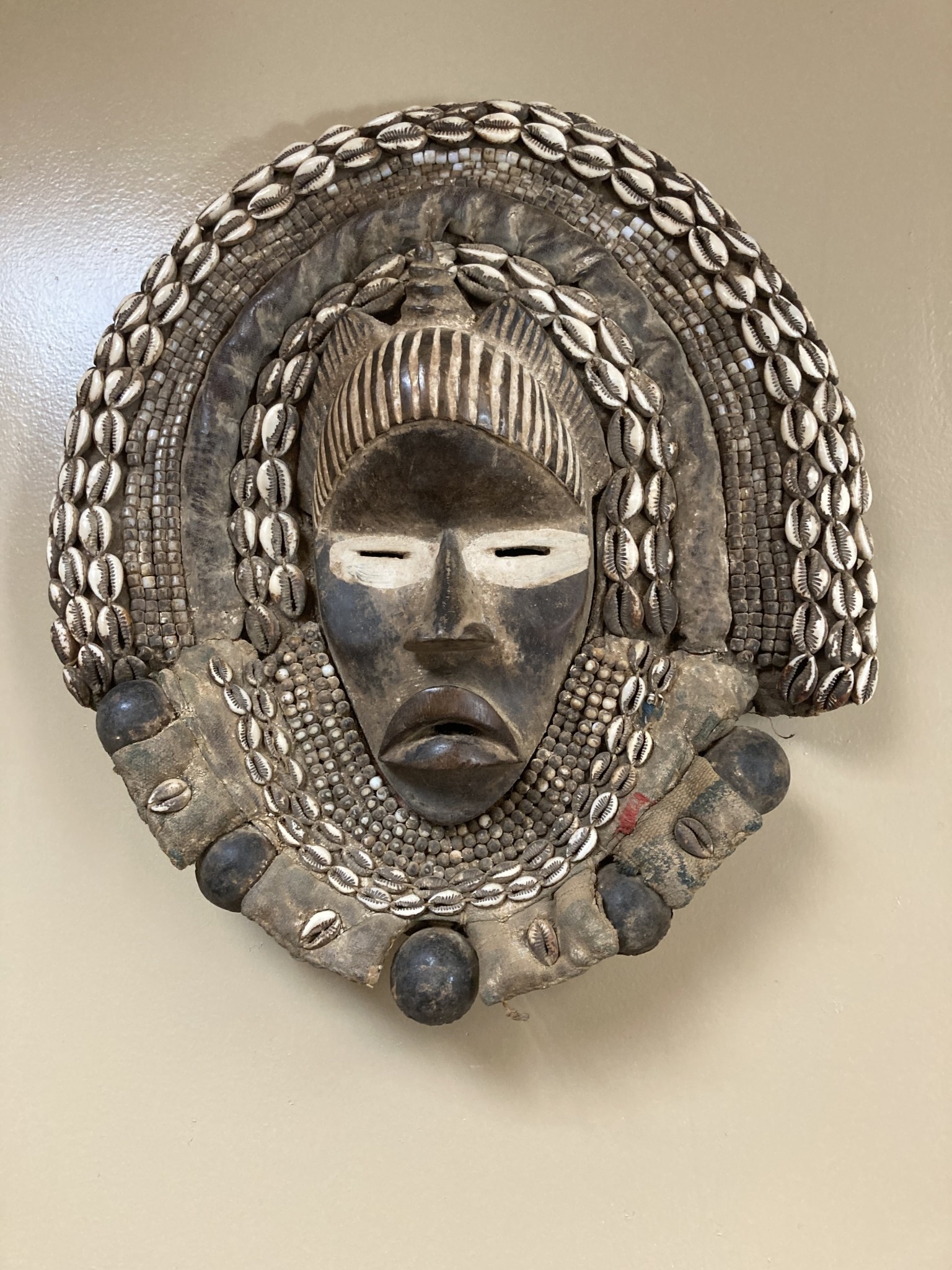 Dan (Yacuba) "Go Ge" mask: The job of this mask is to announce the death of the chief. The dan are found in SW ivory coast and next door in Liberia. Wood, cowrie shells, fabric, and kaolin (white colo