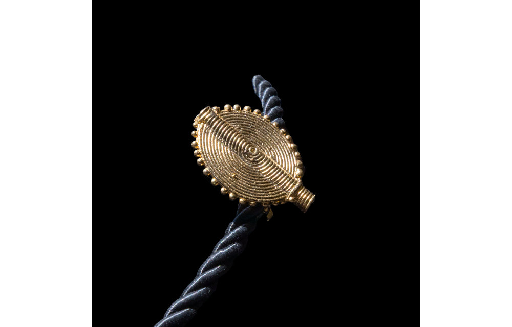 Corded necklace with large brass pendant and clip-on earrings.