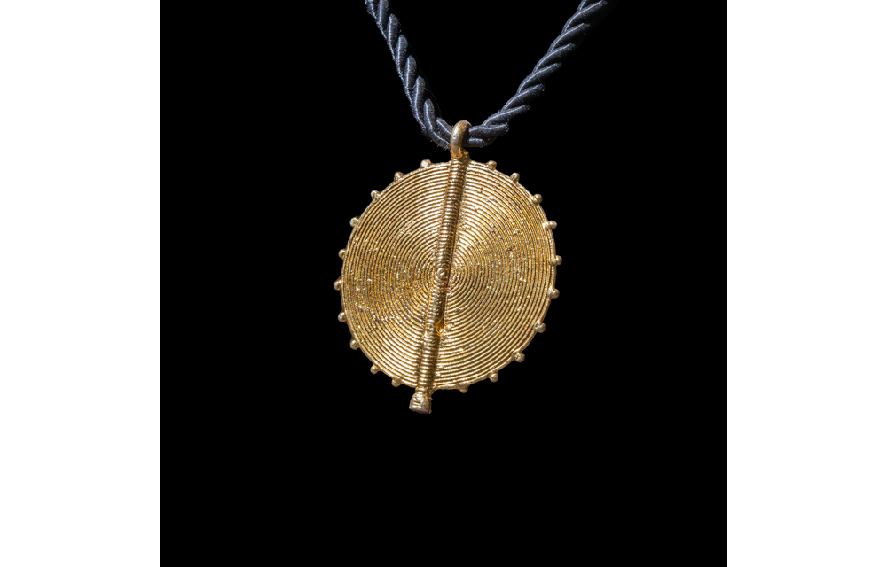 Corded necklace with large brass pendant and clip-on earrings.