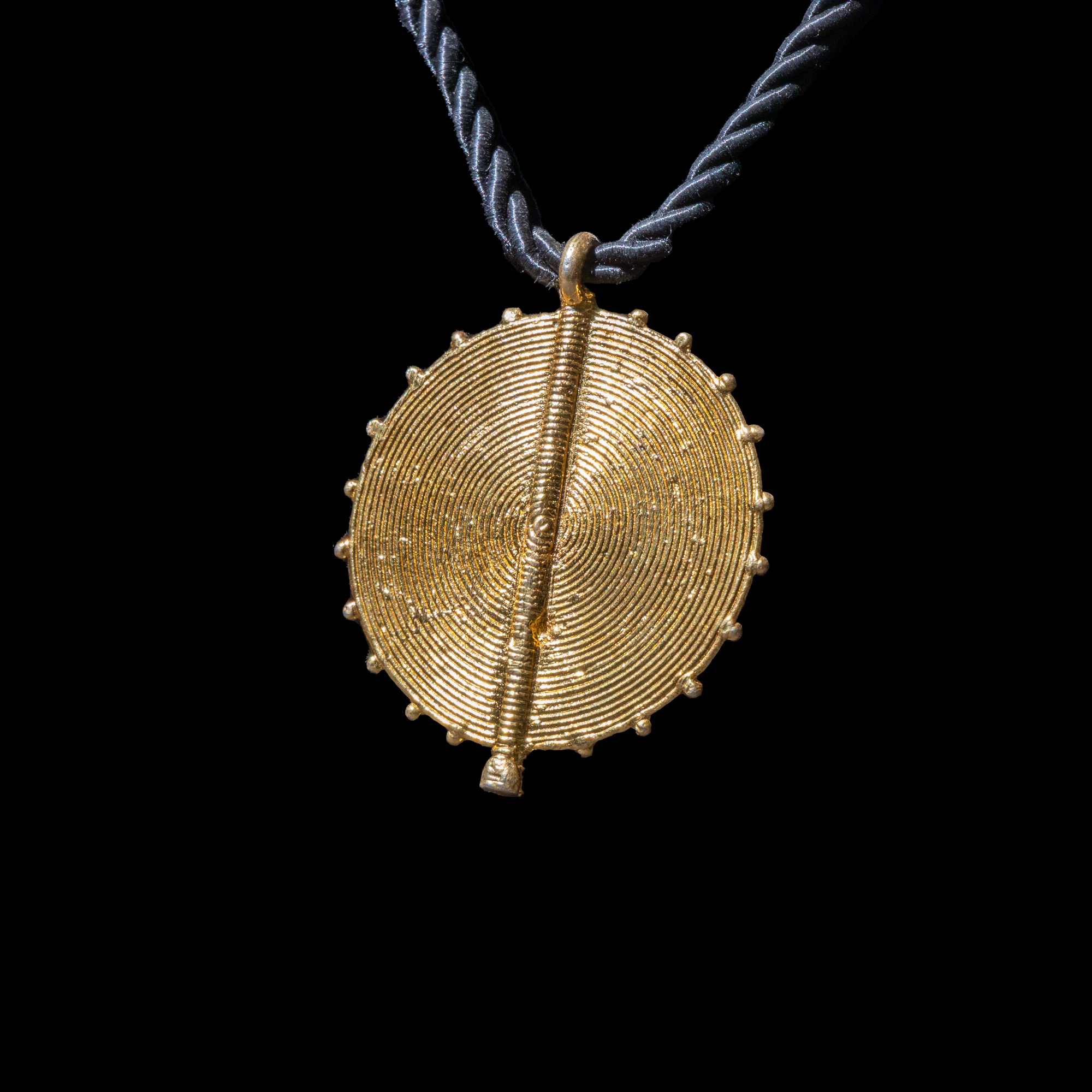 Corded necklace with large brass pendant and clip-on earrings.