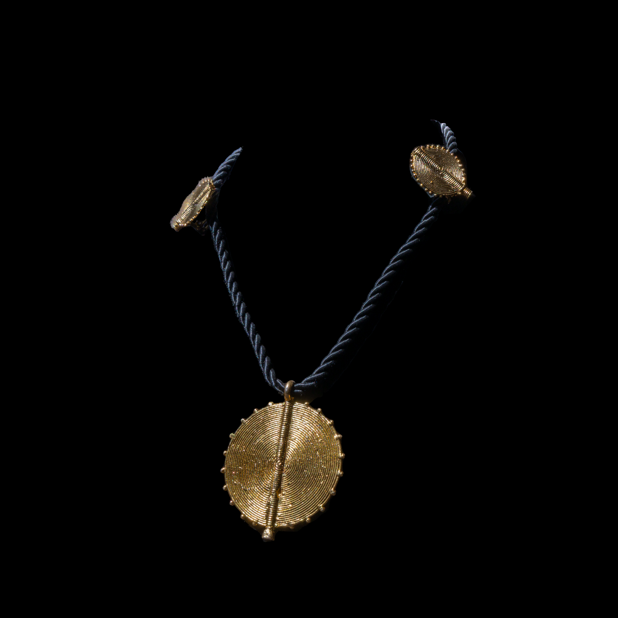 Corded necklace with large brass pendant and clip-on earrings.